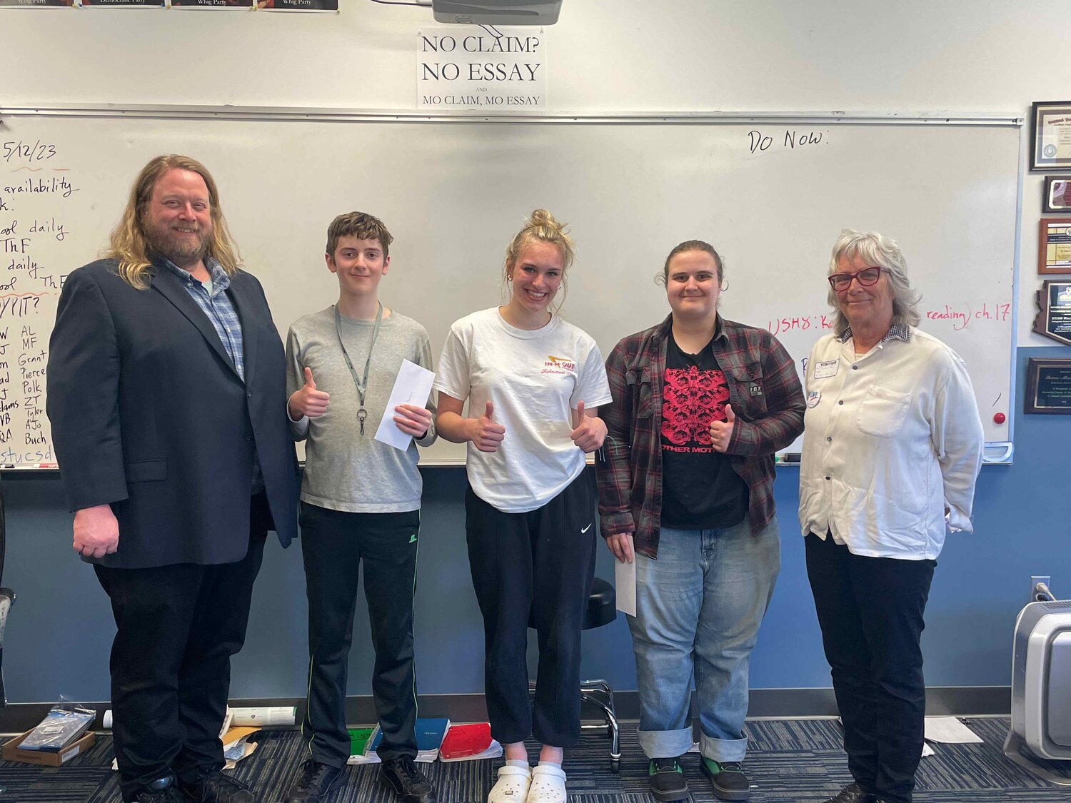 Brian MacKenzie, Chimacum High School teacher, stands with third-place essay winner Keanu Morrison, second-place winner Tessa Richardson, and first-place winner Elliot Pflueger. Also pictured is Jackie Aase, a League of Women Voters-Jefferson County member and Essay Team organizer.